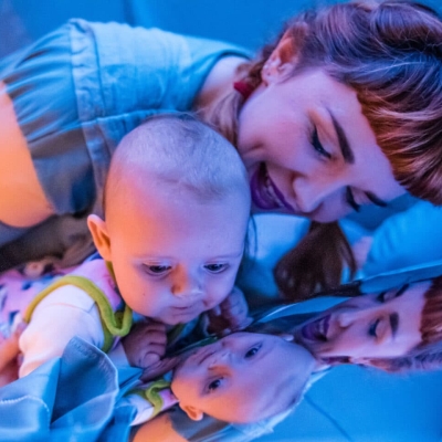 Anna holding a baby looking into a mirror